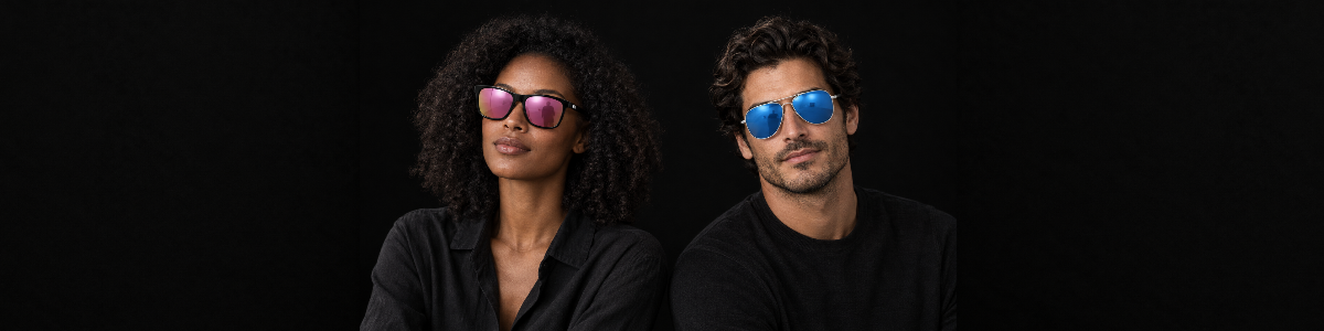 Two models wearing Mayfair pink mirrored sunglasses and Brighton blue mirrored aviator uv polarised sunglasses from Missandtrendy against a dark background