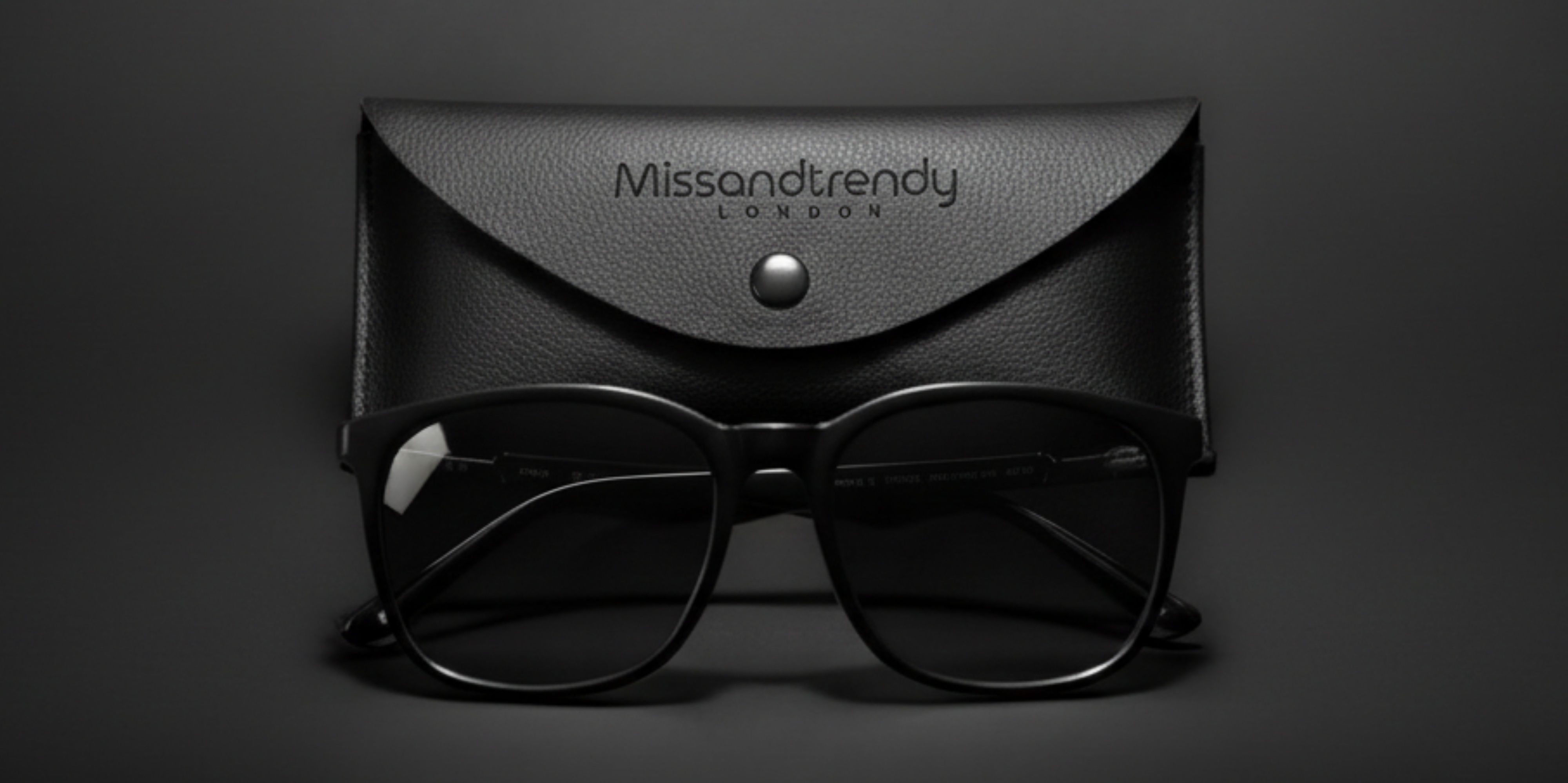Black on black London style UV Polarised Wayfarer sunglasses and a leather black envelop sunglasses case with Missandtrendy logo printed on a luxurious dark background_main
