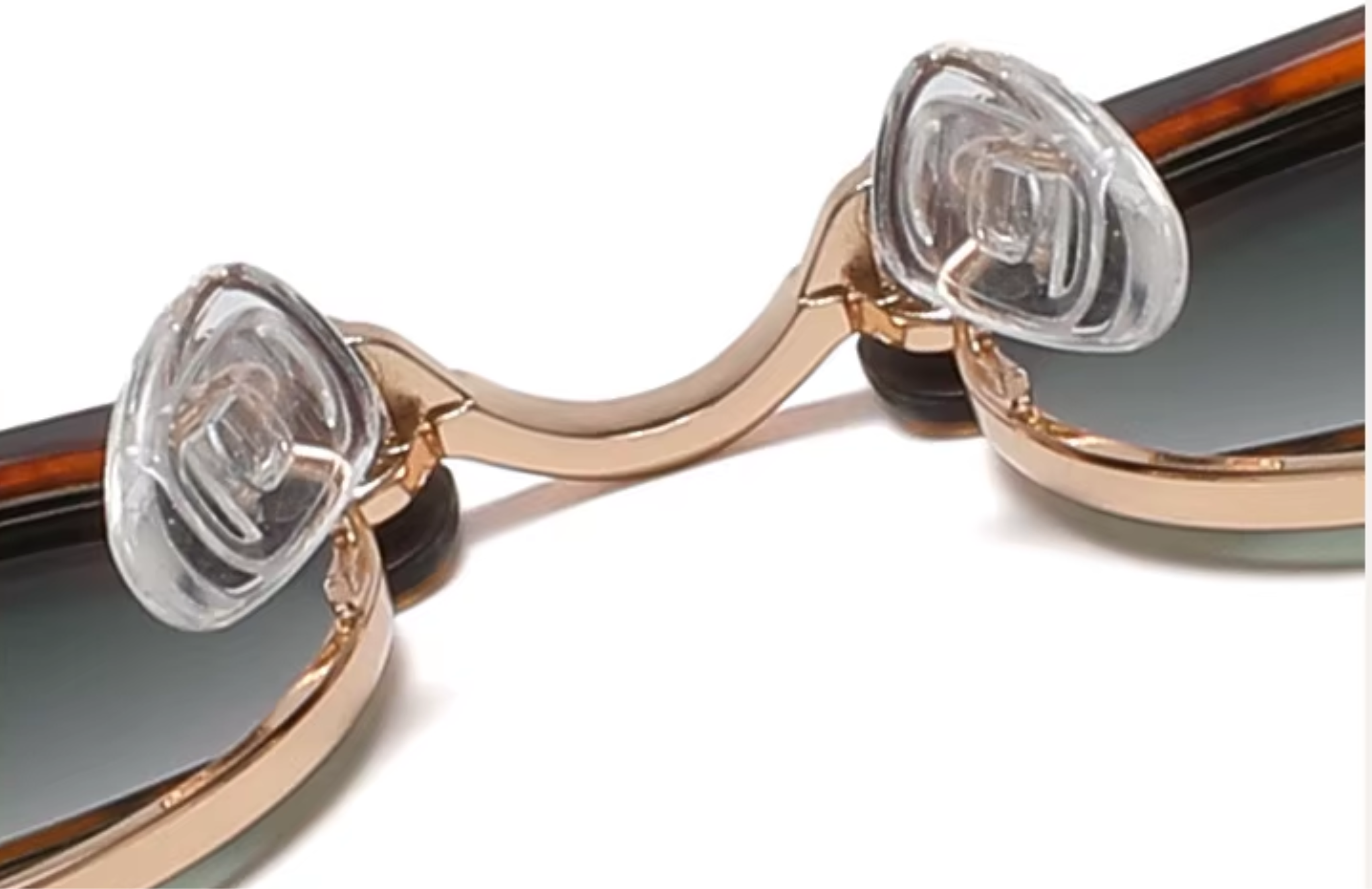 Cardiff - Close-up of a pair of sunglasses with a curved rose gold metal bridge, clear plastic nose pads, and dark lenses on a white background - Missandtrendy
