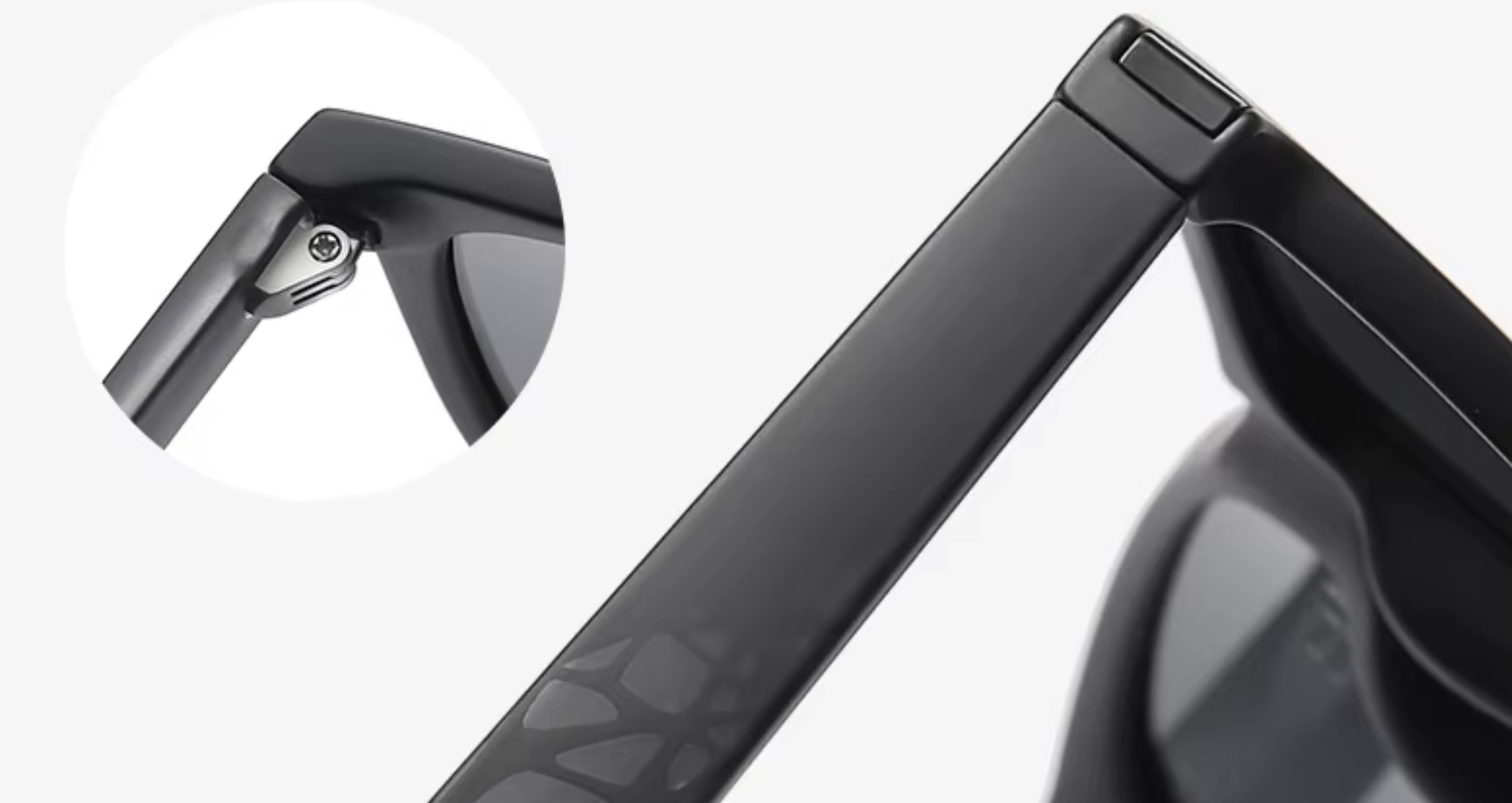 Close-up of a black sunglasses frame showing the hinge and temple arm, with a circular inset detail of the hinge mechanism on a light gray background.