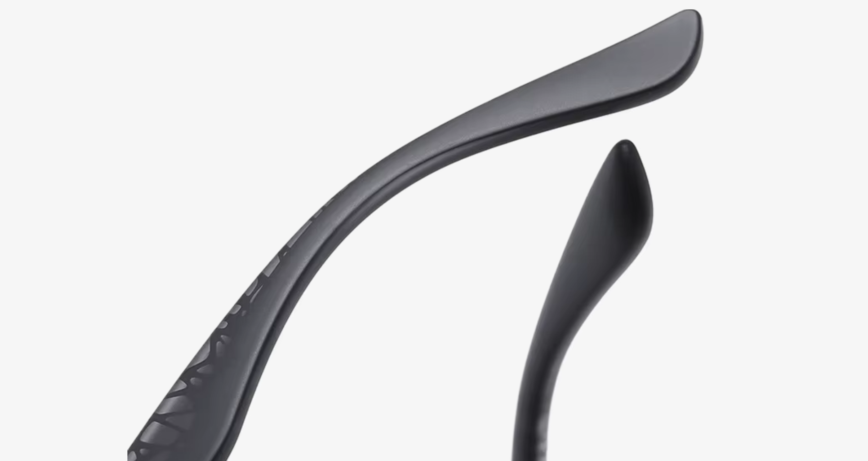 Close-up of black metal eyeglass temple arms on a light gray background.