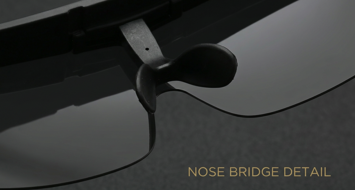 Close-up detail shot of a pair of black sunglasses focusing on the nose bridge area, with the text 'NOSE BRIDGE DETAIL' in gold at the bottom right.