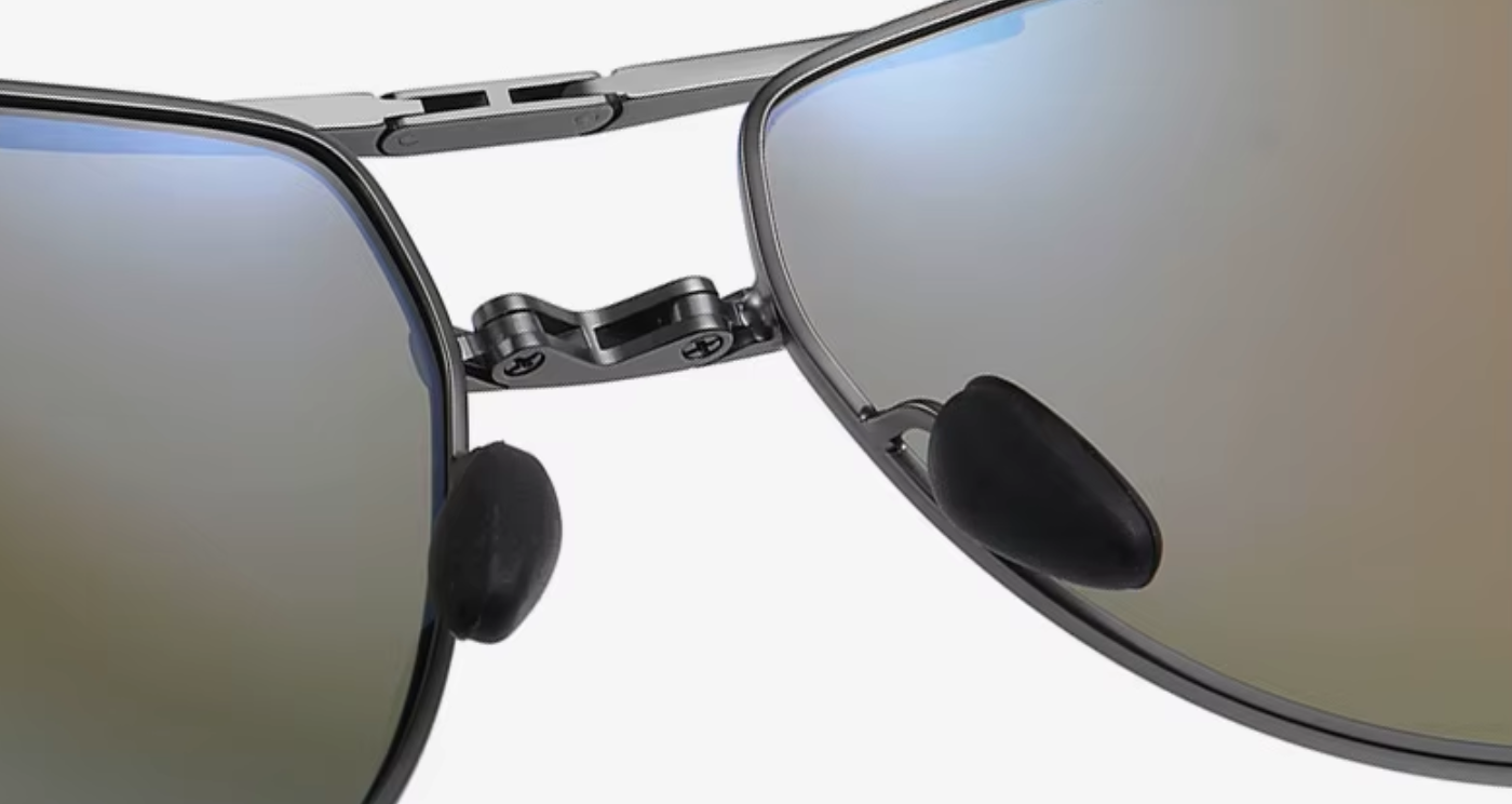 Close-up of a pair of sunglasses with a silver metal frame and mirrored lenses showing a blue-to-gold gradient reflection.